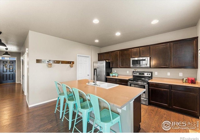 6747 Grainery Rd, Timnath, CO 80547 - kitchen with stainless steel appliances, a sink, dark wood-type flooring, a kitchen bar, and a kitchen island with sink