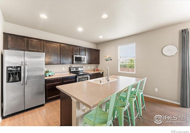6747 Grainery Rd, Timnath, CO 80547 - kitchen featuring stainless steel appliances, a sink, light wood-style floors, dark brown cabinetry, and recessed lighting