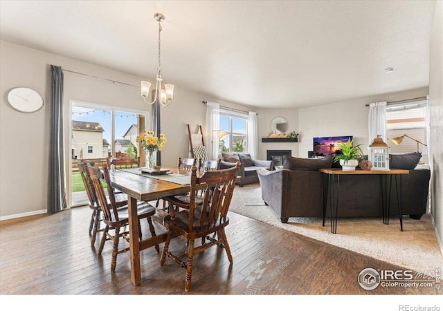 6747 Grainery Rd, Timnath, CO 80547 - dining room featuring wood-type flooring, a glass covered fireplace, a chandelier, and baseboards