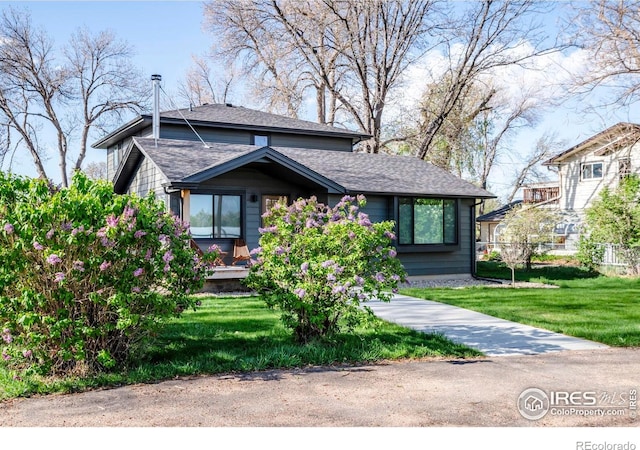 view of front of house with fence, roof with shingles, and a front lawn