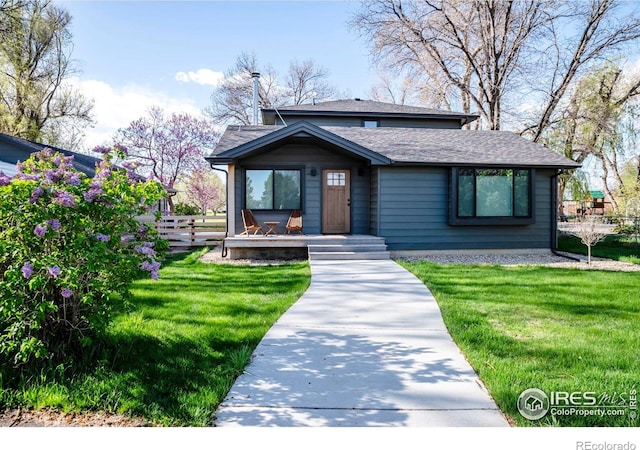 bungalow featuring a porch, roof with shingles, fence, and a front yard