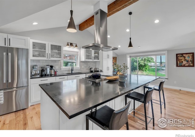 kitchen with dark countertops, lofted ceiling with beams, light wood-style flooring, high end refrigerator, and island range hood
