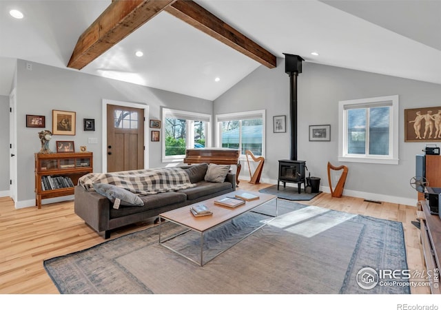 living area featuring vaulted ceiling with beams, a wood stove, recessed lighting, and wood finished floors
