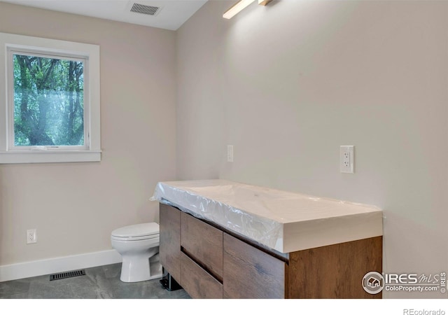 bathroom featuring baseboards, vanity, toilet, and visible vents