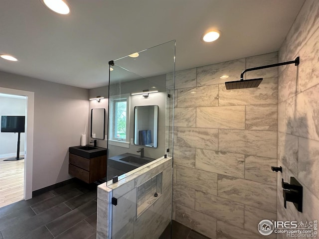 full bath with vanity, baseboards, a tile shower, and recessed lighting