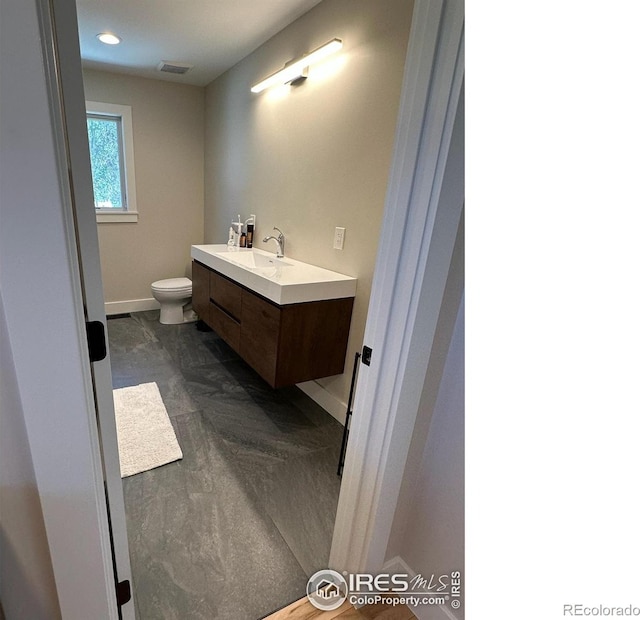 bathroom with toilet, baseboards, visible vents, and vanity
