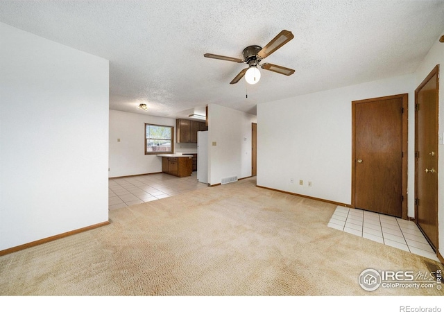 unfurnished living room featuring a textured ceiling, light tile patterned floors, ceiling fan, light carpet, and visible vents