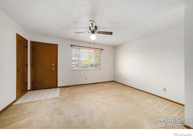 empty room featuring a textured ceiling, carpet flooring, baseboards, and a ceiling fan