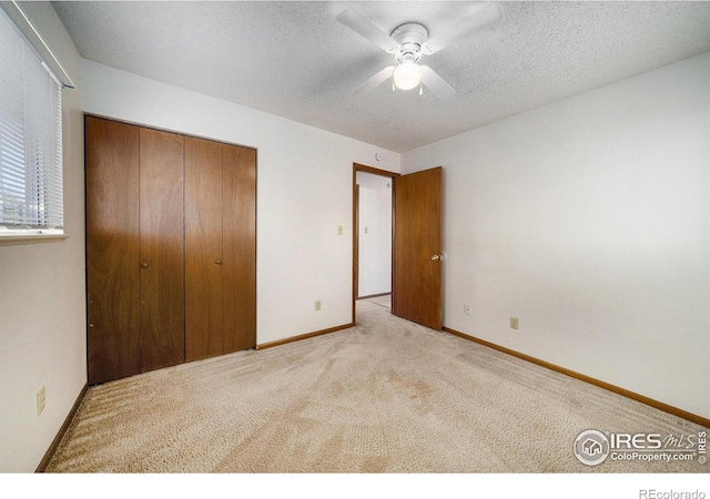 unfurnished bedroom with a textured ceiling, carpet floors, a closet, and baseboards