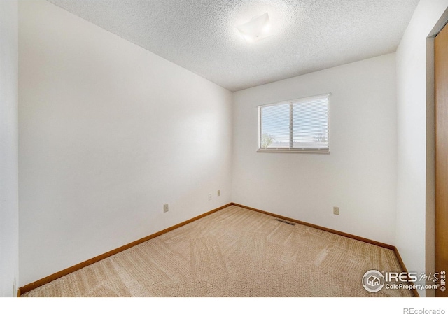spare room with baseboards, a textured ceiling, visible vents, and carpet