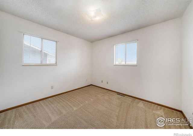 empty room featuring baseboards, visible vents, and carpet flooring