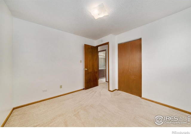 unfurnished bedroom featuring baseboards, carpet flooring, a textured ceiling, and a closet