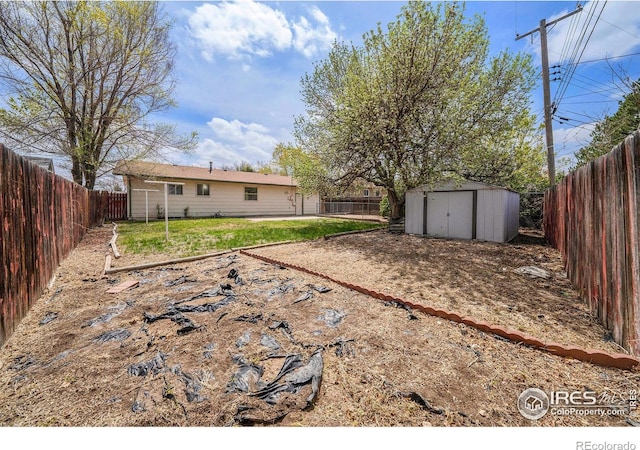 view of yard with a fenced backyard, an outbuilding, and a shed