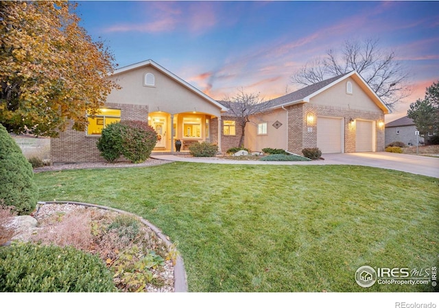 view of front of house with a yard, brick siding, an attached garage, and concrete driveway