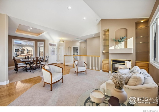 living area featuring built in features, light wood-type flooring, baseboards, a glass covered fireplace, and recessed lighting