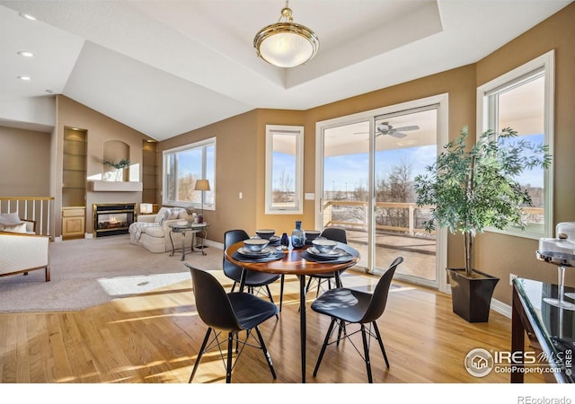 dining room featuring light wood-style floors, baseboards, built in features, and a glass covered fireplace