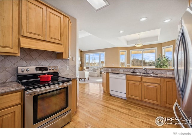 kitchen featuring light wood-style floors, appliances with stainless steel finishes, tasteful backsplash, and a sink