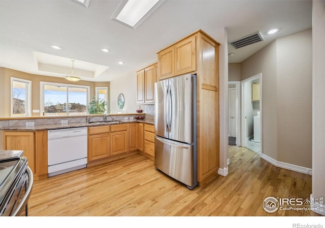 kitchen featuring visible vents, light brown cabinets, a sink, light wood-style flooring, and stainless steel appliances