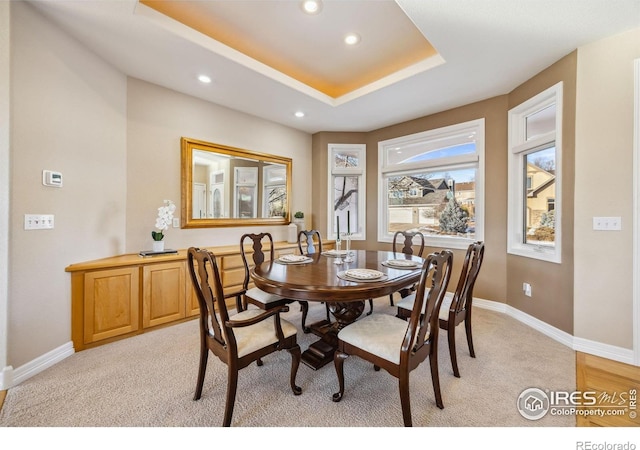dining room featuring a raised ceiling, baseboards, recessed lighting, and light colored carpet