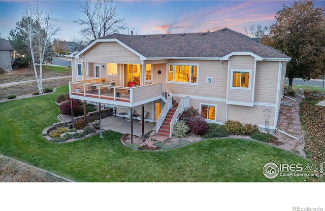 back of house with roof with shingles, a yard, a patio area, and stairway