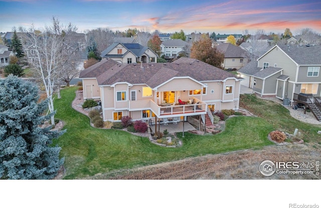 back of property with stairway, a deck, a residential view, and a lawn
