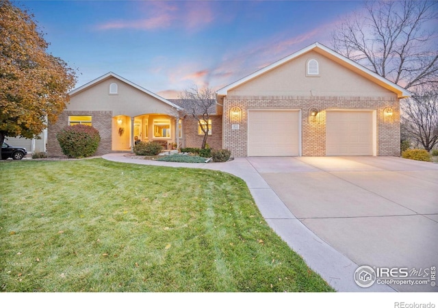 single story home with a lawn, brick siding, concrete driveway, and a garage
