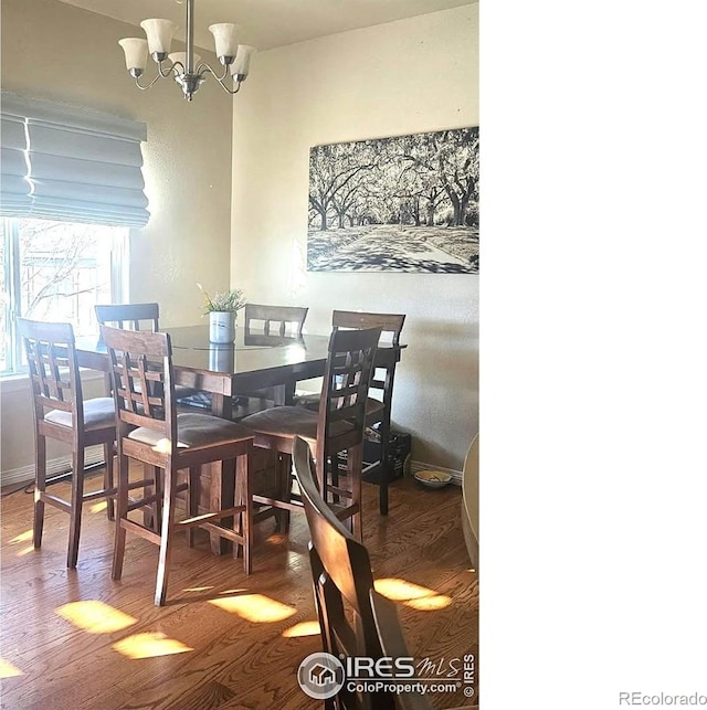 dining space featuring wood finished floors and a chandelier