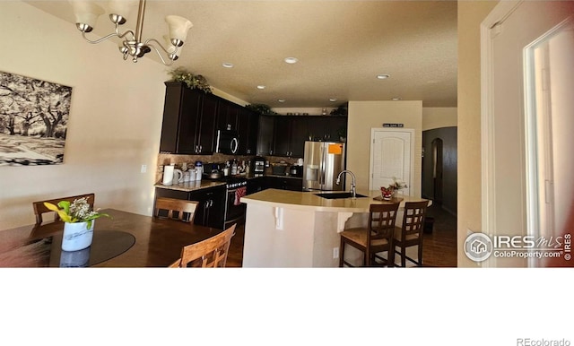 kitchen featuring stainless steel fridge with ice dispenser, a sink, range with gas cooktop, arched walkways, and tasteful backsplash