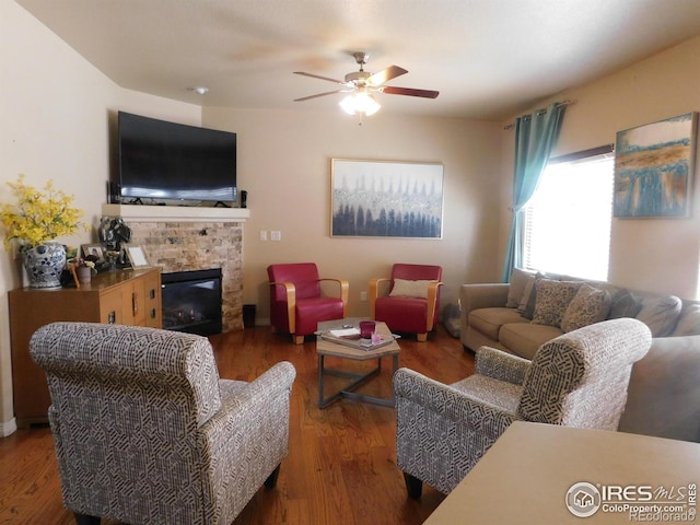 living area with a ceiling fan, a fireplace, and wood finished floors