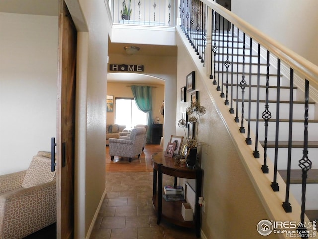 staircase with arched walkways and baseboards