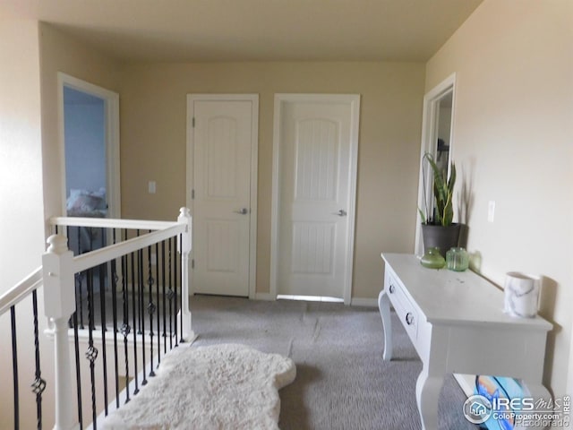 hall with carpet floors, an upstairs landing, and baseboards