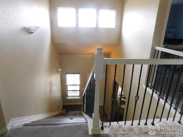 stairs featuring a textured wall and baseboards
