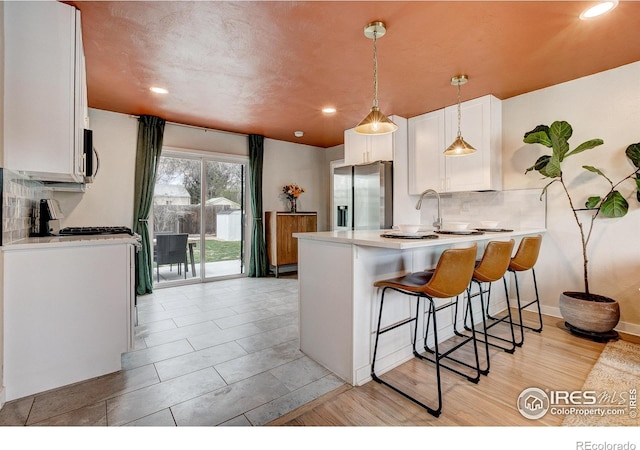 kitchen featuring a peninsula, light countertops, white cabinets, tasteful backsplash, and appliances with stainless steel finishes