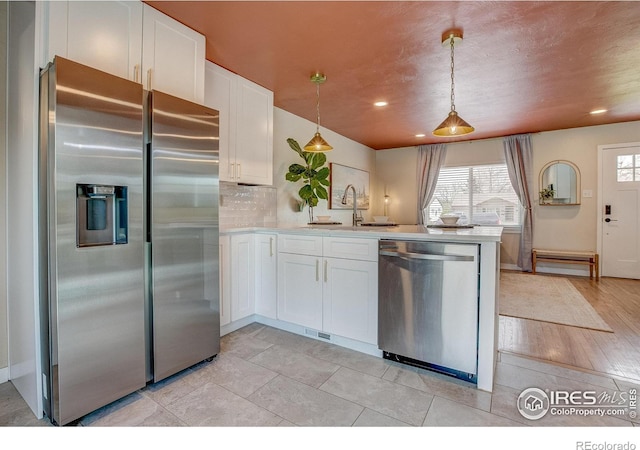 kitchen with white cabinets, a peninsula, appliances with stainless steel finishes, and plenty of natural light
