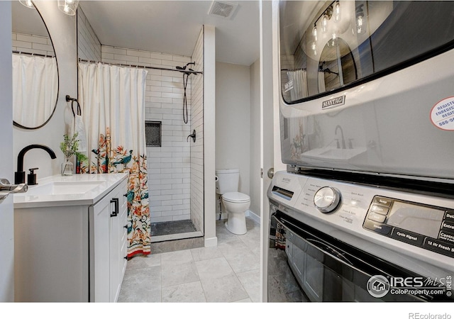 bathroom featuring visible vents, vanity, stacked washer / dryer, toilet, and a shower stall
