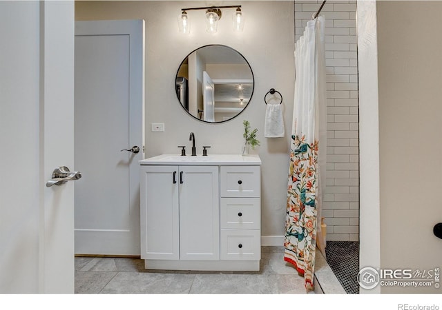 full bathroom featuring baseboards, tile patterned floors, tiled shower, and vanity