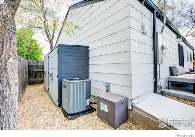 exterior space featuring central air condition unit, fence, and electric meter
