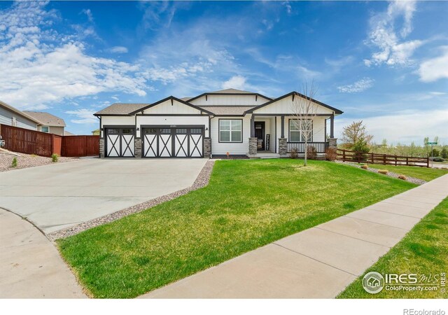 2121 Covered Bridge Pkwy, Windsor, CO 80550 - view of front of home with fence, an attached garage, stone siding, a front yard, and driveway