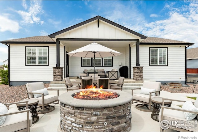 2121 Covered Bridge Pkwy, Windsor, CO 80550 - rear view of house with board and batten siding, a patio area, roof with shingles, and an outdoor living space with a fire pit