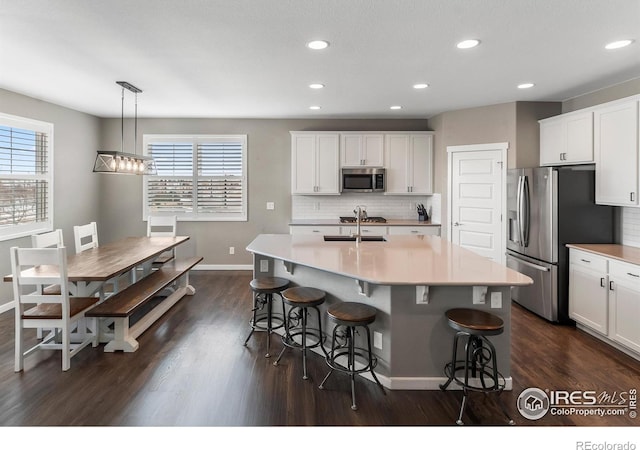 2121 Covered Bridge Pkwy, Windsor, CO 80550 - kitchen with backsplash, a breakfast bar area, appliances with stainless steel finishes, and dark wood-type flooring