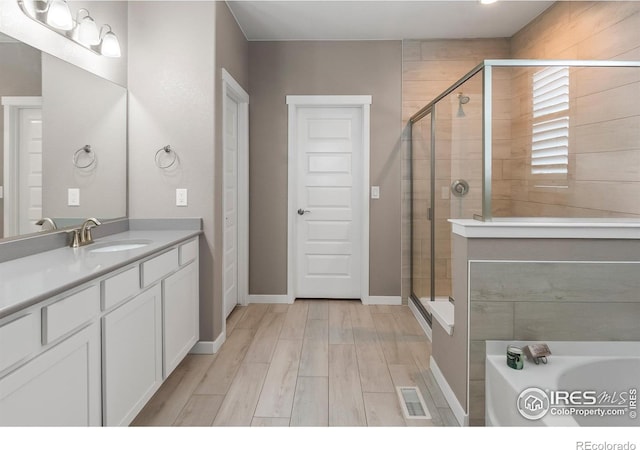 2121 Covered Bridge Pkwy, Windsor, CO 80550 - full bathroom featuring vanity, a stall shower, wood finished floors, and visible vents
