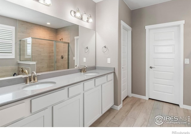 2121 Covered Bridge Pkwy, Windsor, CO 80550 - full bathroom featuring wood finished floors, double vanity, a sink, and a stall shower