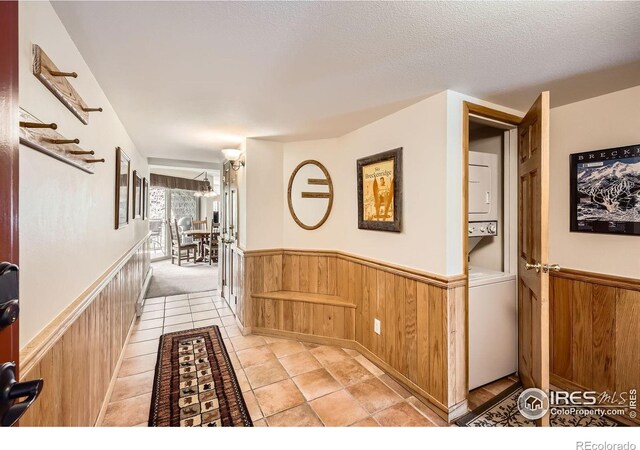 755 Columbine Rd Unit 303, Breckenridge, CO 80424 - hall featuring wainscoting, stacked washer / drying machine, wooden walls, a textured ceiling, and light tile patterned floors