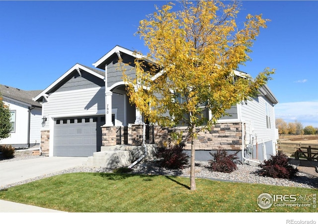 craftsman-style home with a front lawn, driveway, and stone siding