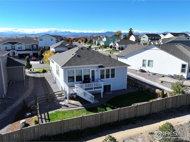 rear view of house featuring a residential view, cooling unit, a fenced backyard, and roof with shingles