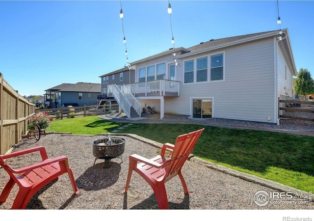 back of house with a lawn, a deck, stairway, a fenced backyard, and a fire pit
