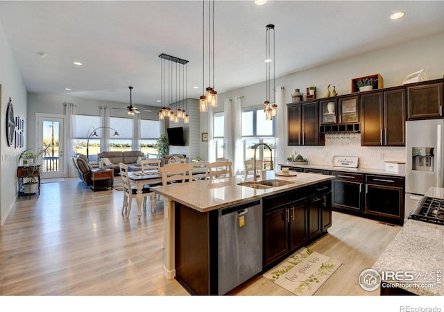 kitchen featuring light wood-style floors, open floor plan, tasteful backsplash, a sink, and stainless steel appliances