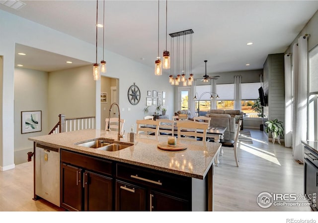 kitchen featuring a sink, light wood finished floors, decorative light fixtures, open floor plan, and visible vents