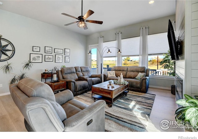 living room featuring a ceiling fan, a fireplace, baseboards, recessed lighting, and light wood-style flooring