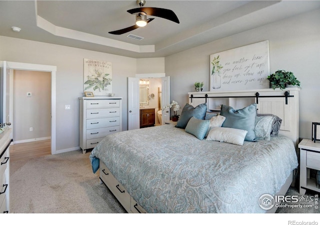 bedroom with connected bathroom, ceiling fan, light colored carpet, a raised ceiling, and visible vents